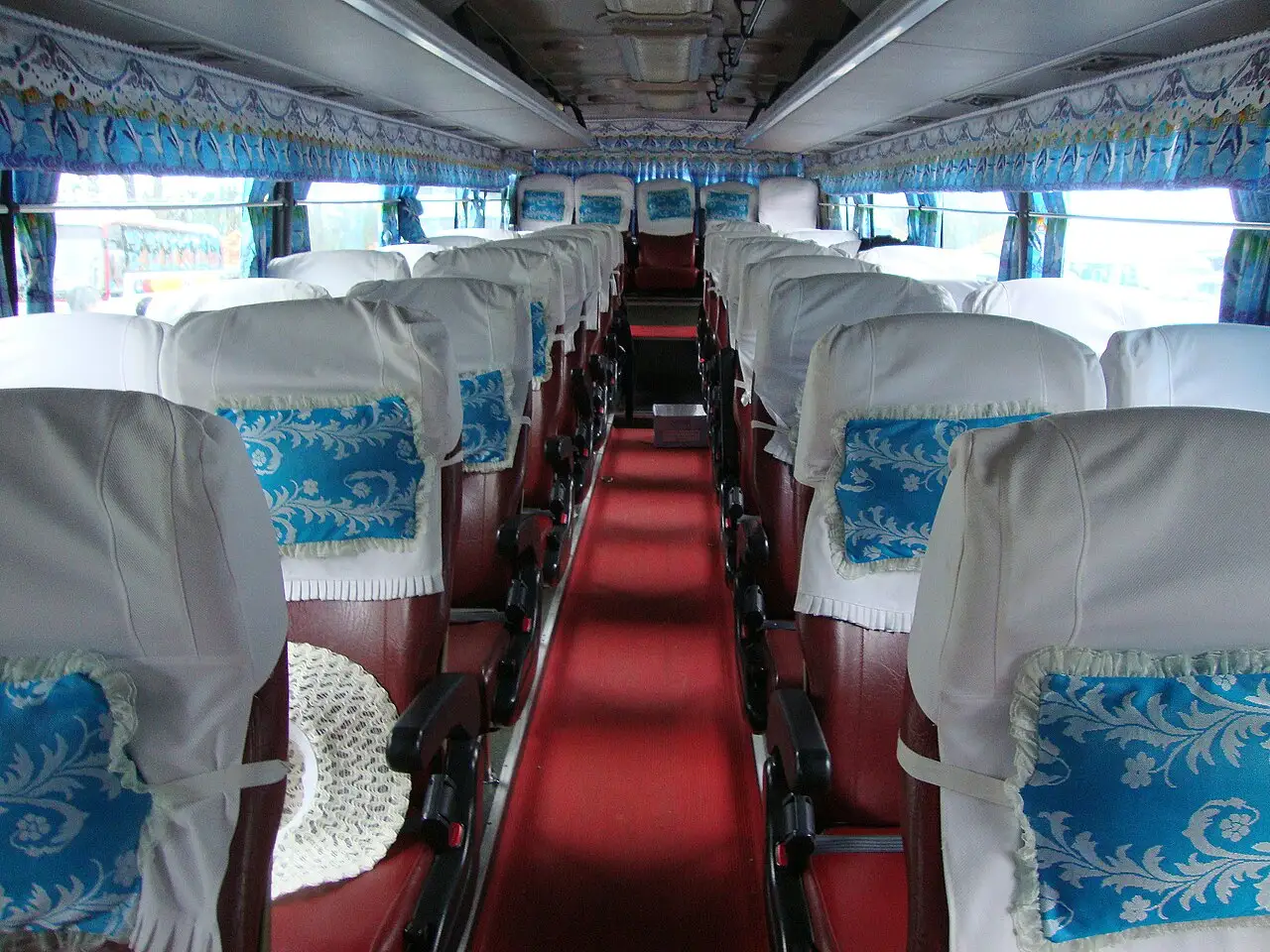 Rows of reclining coach seats with lace headrest covers inside a Hyundai Aero Express Hi-Class bus in Vietnam